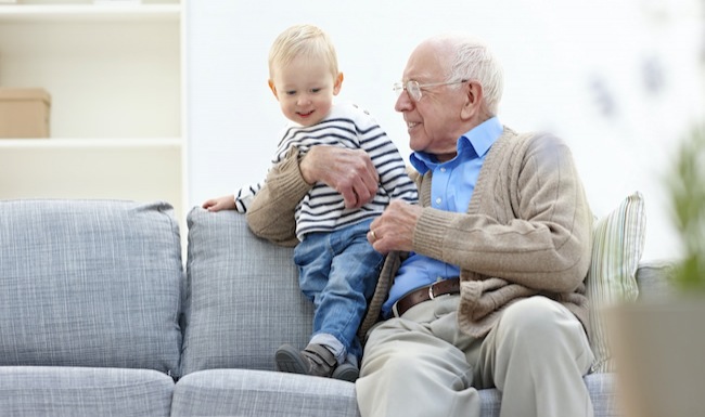 Senior man and toddler sitting on a brightly lit couch